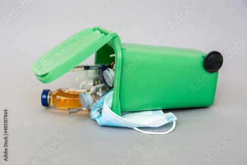 trash container with medical waste, end of the pandemic. syringe, ampoule, vaccine, face mask - medical pandemic items photo