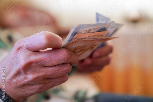 Closeup of wrinkled hands holding turkish lira banknotes 