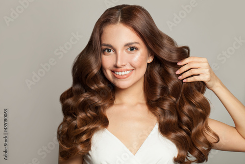 Tablou pe pânză Portrait of beautiful woman touching her long healthy curly hair and looking at