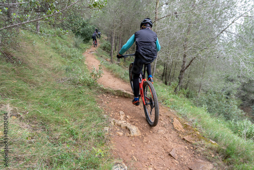 Rear view of a cyclist practicing mountain biking on a forest path