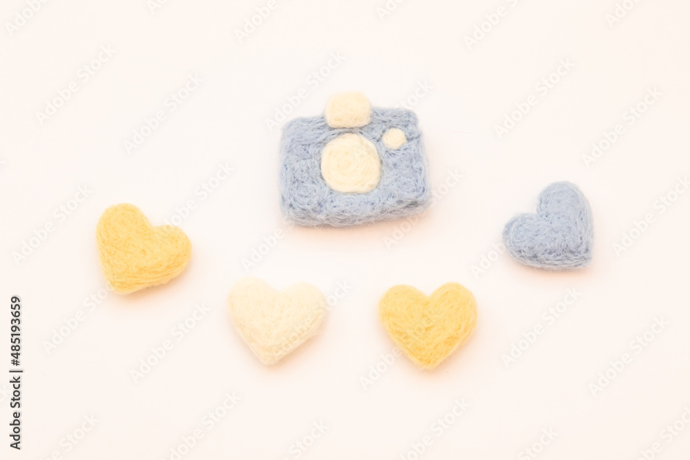 Obraz premium Four hearts and a felted camera on a white background. Felted toys. Handmade requisites