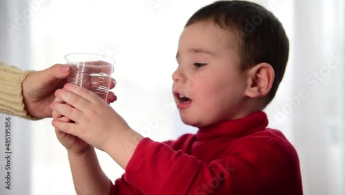 Close-up of a child taking a glass of juice from his mother's hands