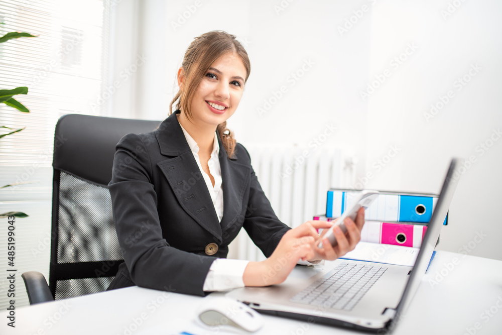 Woman using her cellphone in her office Woman using her cellphone in her office
