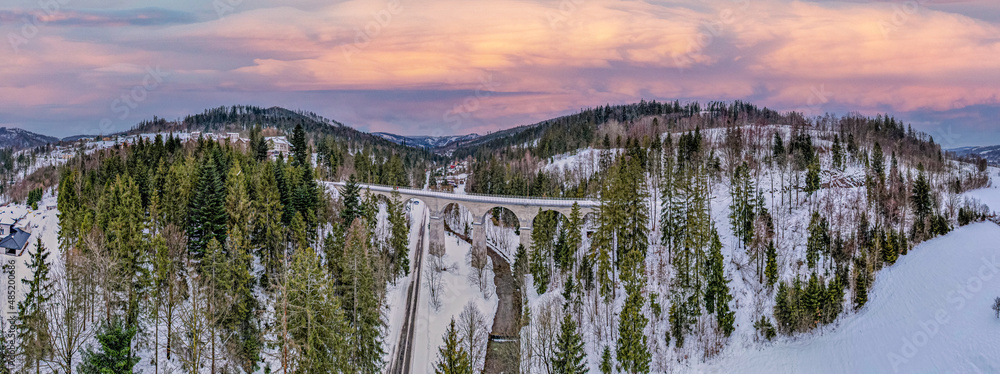 Wiadukt kolejowy w górach zimą nad rzeką i drogą. Wisła, Beskid Śląski w Polsce - obrazy, fototapety, plakaty 