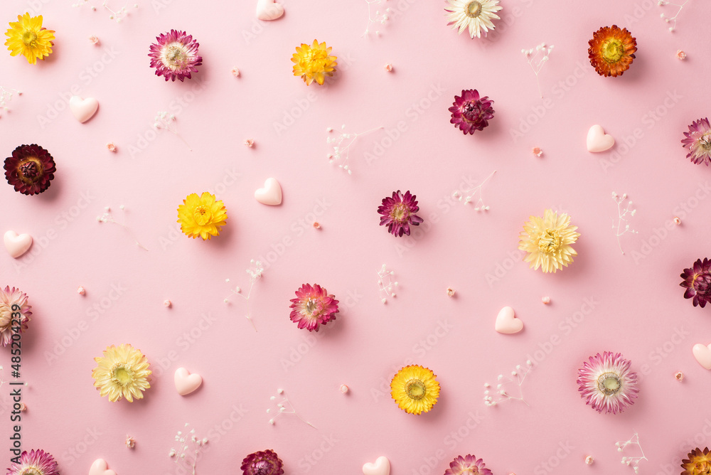 Top view photo of the many different colorful flowers with branches of gypsophila and pink volume confetti in shape of hearts scattered on the pastel pink background Top view photo of the many different colorful flowers with branches of gypsophila and pink volume confetti in shape of hearts scattered on the pastel pink background