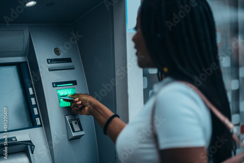 Photos Beautiful african american woman using atm machine and a credit card