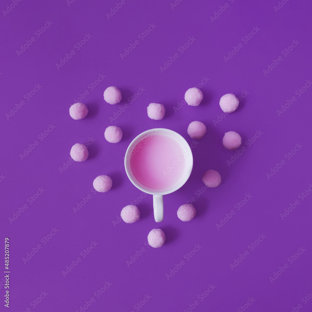 Valentine's Day flat lay concept. Cup with pink drink and pink pom poms are making heart shape against violet background. Valentine's Day flat lay concept. Cup with pink drink and pink pom poms are making heart shape against violet background.