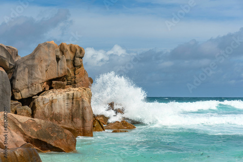 A tropical scenery with rough sea waves splashing against rock formation on the shore