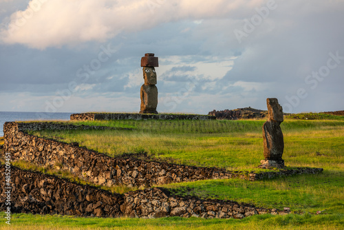 Zwei Moais in Ahu Tahai mit Korallenaugen und einem roten Hut, den Pukau, an der Küste von Hanga Roa auf Rapa Nui photo