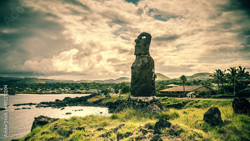 Ein Moai an der Küste von Rapa Nui mit Korallenaugen vor dramatischem Himmel photo