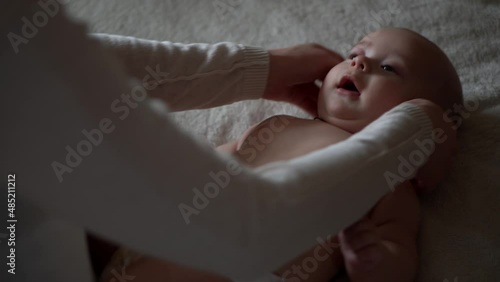 Newborn Baby And Young Mom Lie On Bed. Cute Smiling Teethless Kid Face Portrait. Woman Makes Massage Naked Child. Mother Care Of Babe. Infant, Mother Day, Childbirth, Beginning, Relationship Concept photo