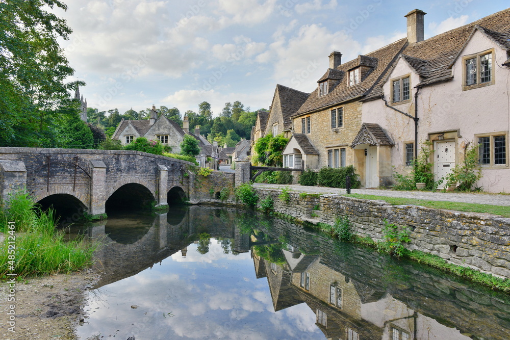 Scenic view of traditional old cottage houses by a river in a beautiful English village - namely the landmark village of Castle Combe in Wiltshire England