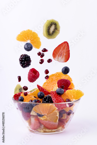 the fresh fruit mixed into pieces falls into the glass bowl. White background