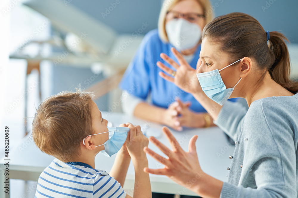 Mother with nervous son in child psychologist in mask Mother with nervous son in child psychologist in mask
