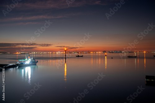 A harbor in the dawn sky with a lighthouse visible 
