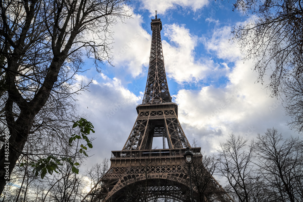 eiffel tower in paris through trees of champ du mars and close up