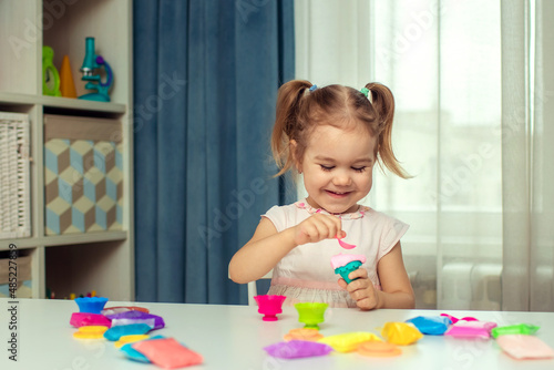 Happy little girl sculpts plasticine and learns.