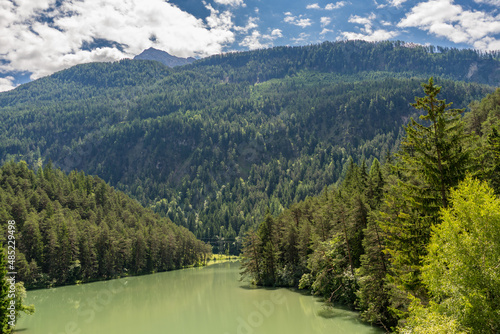 grüner Bergsee zwischen Wäldern und Bergen  photo