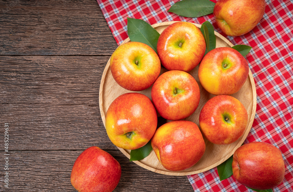 Red apple in wooden plate on wooden background, US. Red Envy apple on wooden table. Red apple in wooden plate on wooden background, US. Red Envy apple on wooden table.