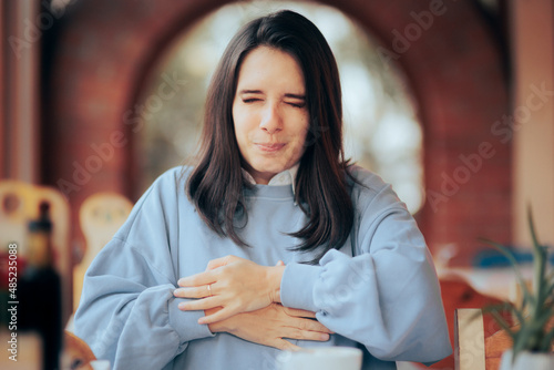 Woman Having a Stomachache at the Restaurant after Eating  photo