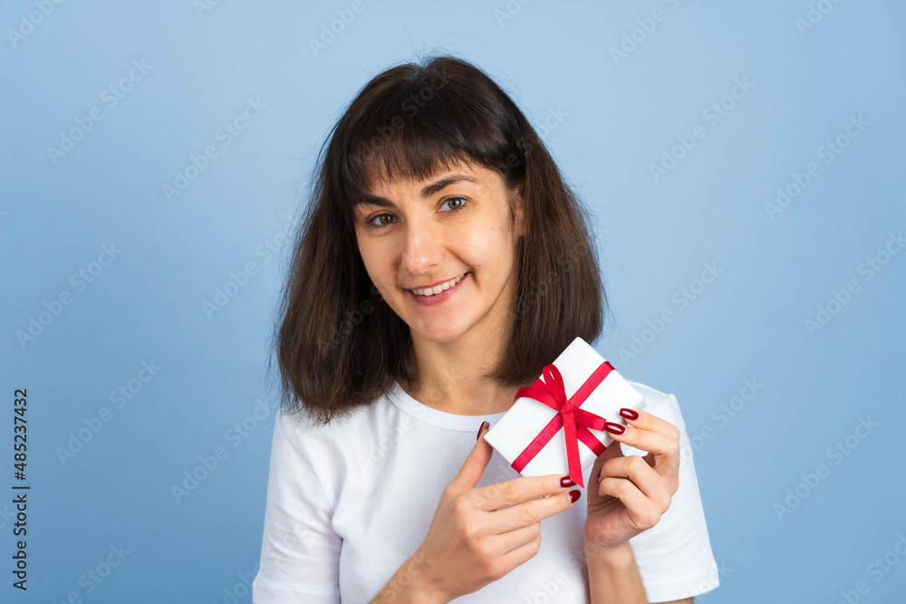 Smiling happy woman holding gift box isolated on blue background. Valentines day or birthday concept Smiling happy woman holding gift box isolated on blue background. Valentines day or birthday concept