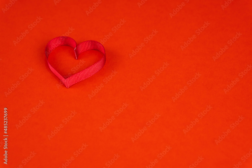Valentine's Day or birthday concept with copy space. Red ribbon heart on red papper