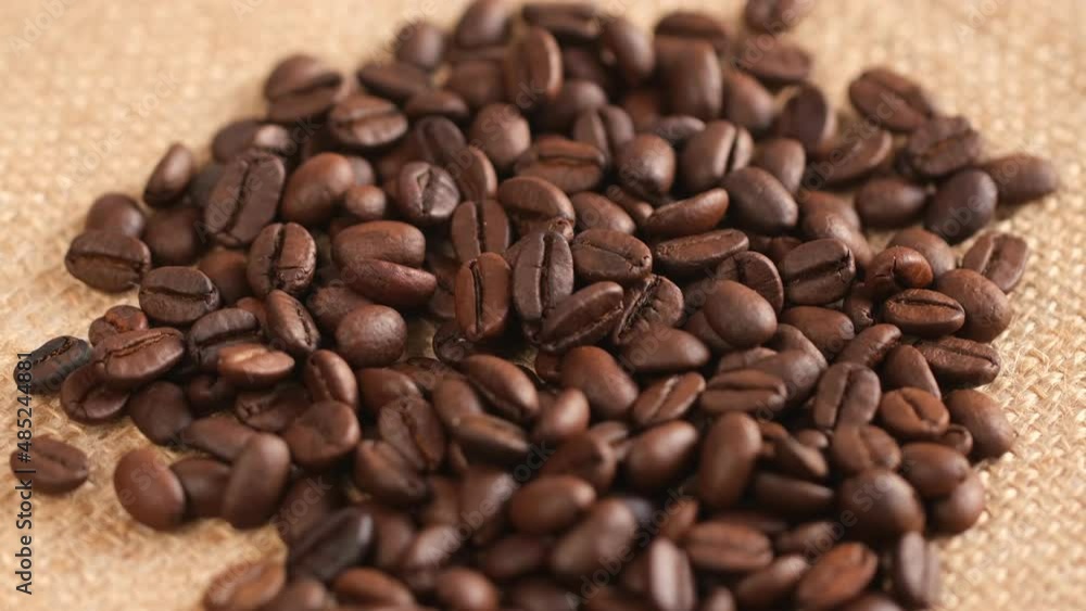 Coffee beans on canvas, cam moves , close up.Freshly roasted coffee on canvas.Coffee beans in the bag.A handful of coffee beans on a brown canvas. Coffee beans on canvas, cam moves , close up.Freshly roasted coffee on canvas.Coffee beans in the bag.A handful of coffee beans on a brown canvas.