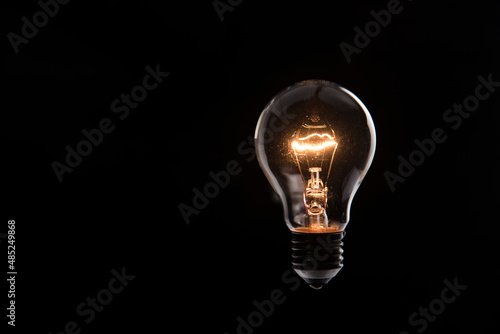 Cuadro en lienzo tungsten light bulb lit on black background