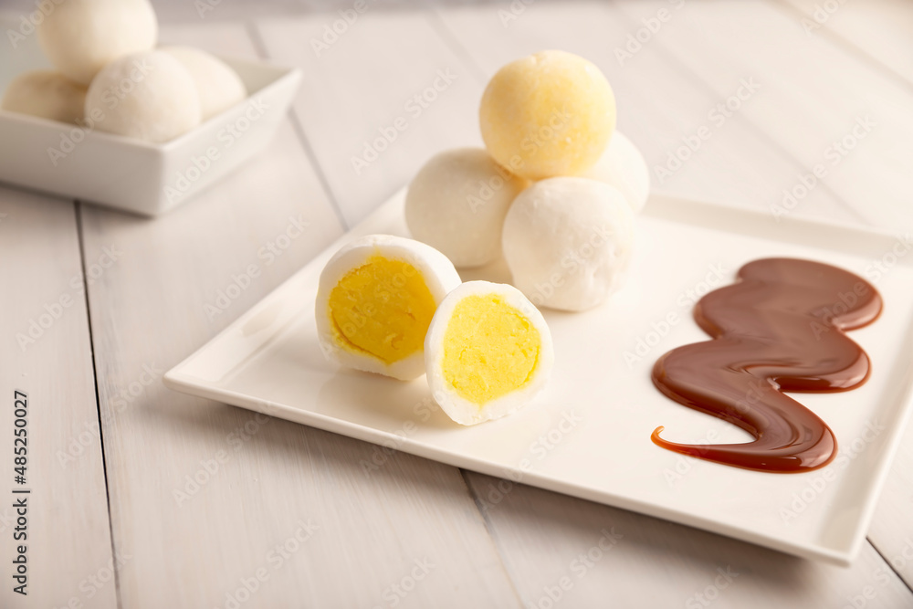 Ice cream mini Mochi with caramel (cajeta). Traditional Japanese dessert made from rice flour. Close up on white wooden surface. Ice cream mini Mochi with caramel (cajeta). Traditional Japanese dessert made from rice flour. Close up on white wooden surface.