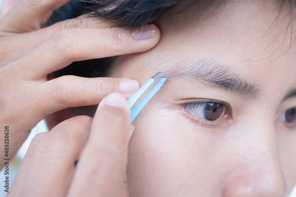 Woman plucking eyebrows with tweezers close up. authentic brown eyes black hair and skin tan asian Thailand. beauty cosmetic concept. Woman plucking eyebrows with tweezers close up. authentic brown eyes black hair and skin tan asian Thailand. beauty cosmetic concept.