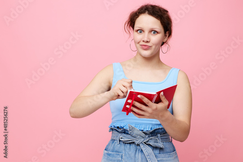 teenager girl writing in a red notebook with a pen study close-up unaltered