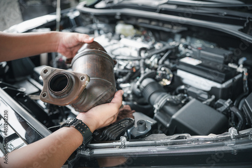 Fotografie Close up old catalytic converter in hand Car service man remove from engine gaso