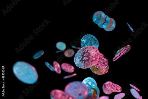 falling bitcoins with blue and pink light on dark background photo