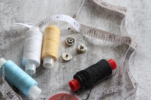 A set of seamstresses, threads, needles, buttons and a meter. Photo on a gray background. Ideal for a sewing workshop. photo