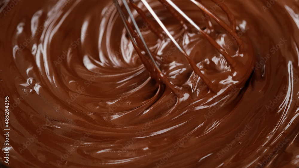 Stirring melted liquid chocolate with steel whisk. Mixing molten chocolate or dark caramel. Cooking chocolate dessert Stirring melted liquid chocolate with steel whisk. Mixing molten chocolate or dark caramel. Cooking chocolate dessert