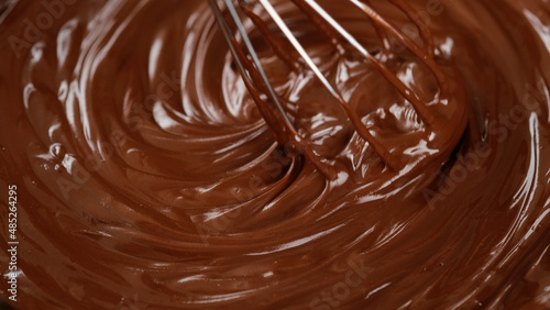 Stirring melted liquid chocolate with steel whisk. Mixing molten chocolate or dark caramel. Cooking chocolate dessert