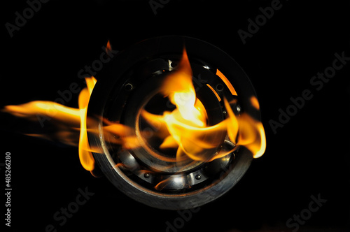 Metal ball bearing in a bright flame on a black background.