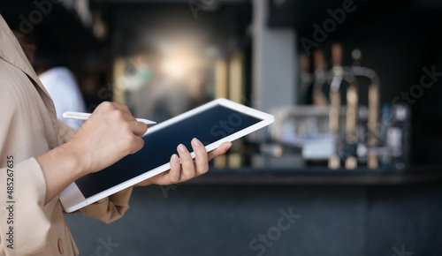 Young asian woman using digital tablet working online and standing in front of the counter in her shop   Concept business owner working in her small business
