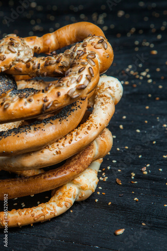 Obraz na płótnie Fresh prepared homemade soft pretzels. Different types of baked bagels with seeds on a black background. w salonie