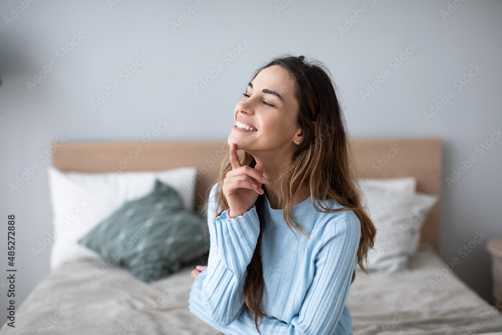 Cute woman in casual clothes smiling sitting on the bed. Cozy home Cute woman in casual clothes smiling sitting on the bed. Cozy home