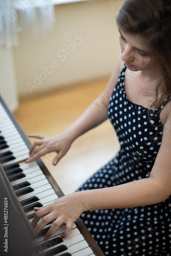 A young woman plays the piano in the privacy of her home.