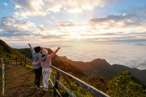 Young couple travelers looking at the sunrise and the sea of mist on the mountain in the morning, Travel lifestyle concept