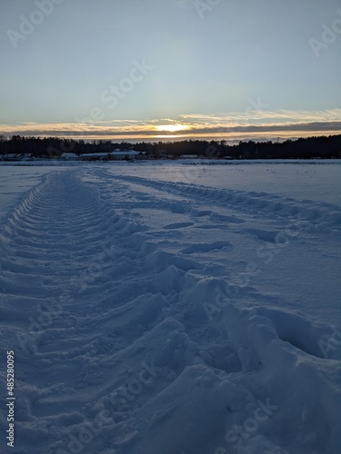 sunsen over the snow field with truck trails