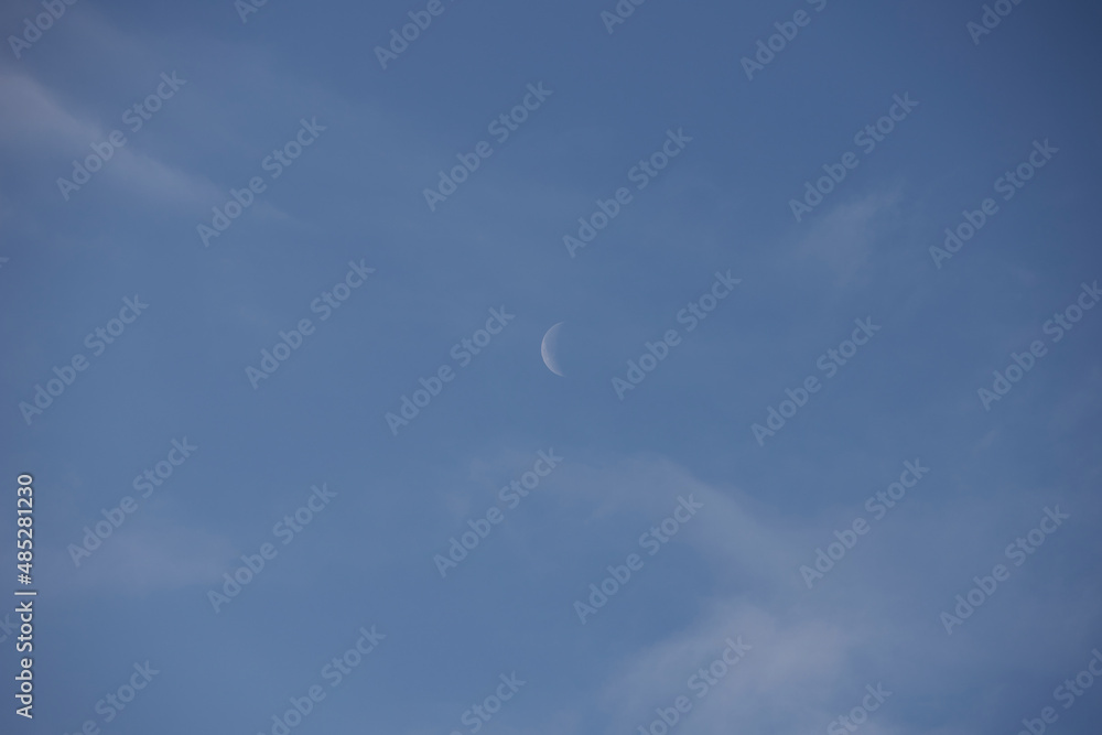 half moon in the day, blue sky with a few clouds half moon in the day, blue sky with a few clouds