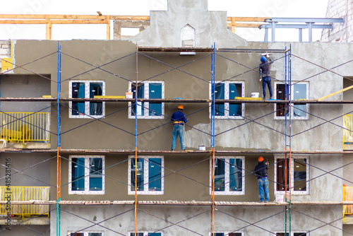 High-rise builders work on makeshift log scaffolds without insurance