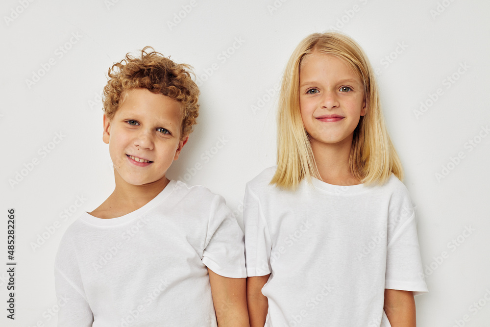 Little boy and girl in white T-shirts are standing next to Lifestyle unaltered Little boy and girl in white T-shirts are standing next to Lifestyle unaltered