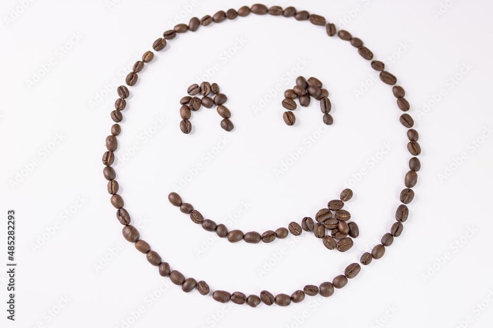 Cheerful emoticon made from coffee beans on a white background Cheerful emoticon made from coffee beans on a white background