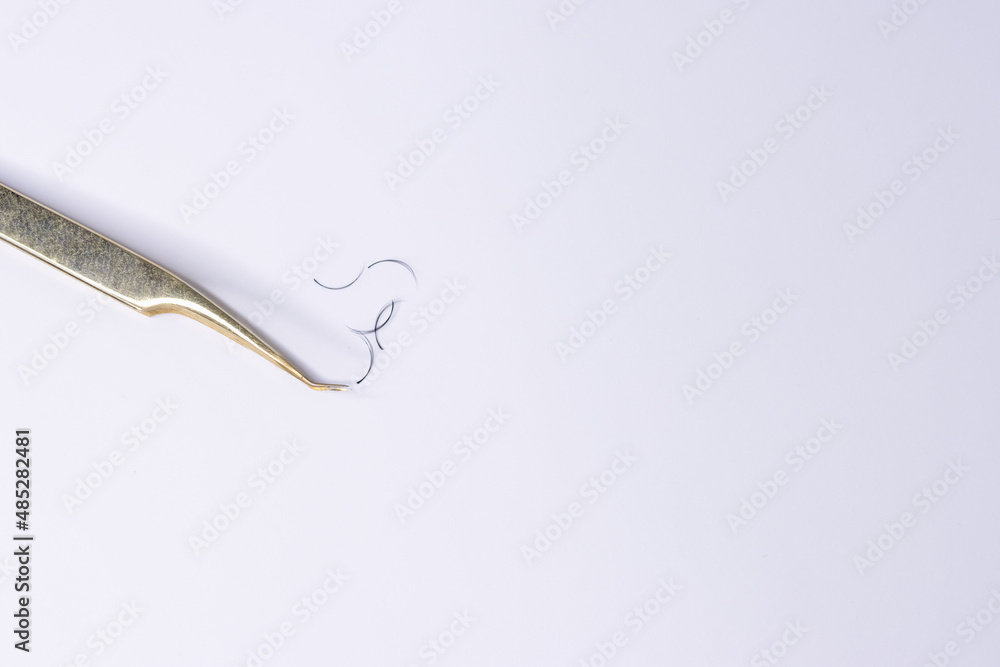 On a white background lies tweezers for eyelash extensions, eyelashes On a white background lies tweezers for eyelash extensions, eyelashes