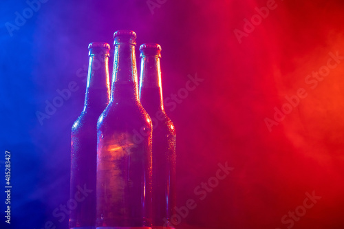 Three bottles of beer in a blue-pink mist.