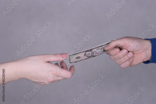 hands giving money 5 dollars isolated on gray background close-up. photo